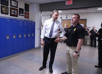 Attorney General Dave Yost listens as Ontario Police Lt. Tony Grimwood describes how a training scenario will play out at a high school in the city, west of Mansfield.